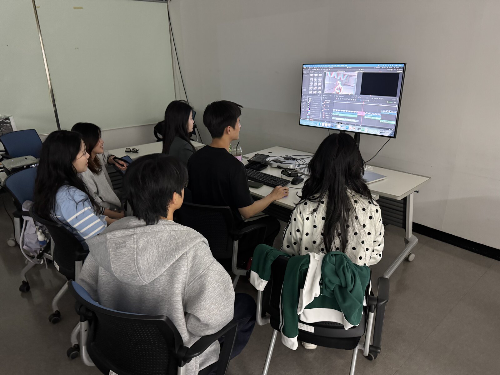 Students gathered around a monitor displaying a DaVinci Resolve edit